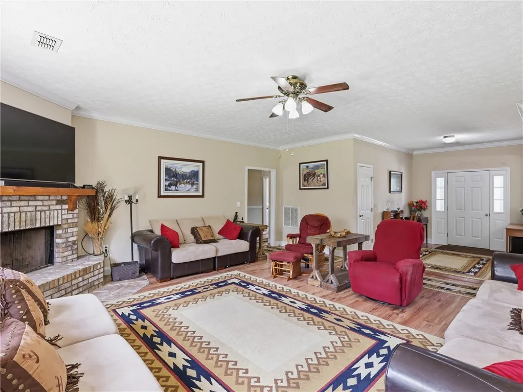A welcoming living area boasts warm wood-tone flooring, a cozy fireplace, and crown molding.