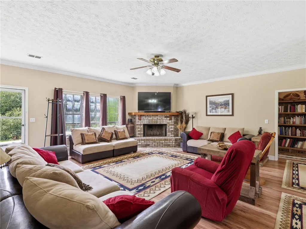 A welcoming living area boasts a cozy brick fireplace and rich wood flooring, perfect for gatherings.