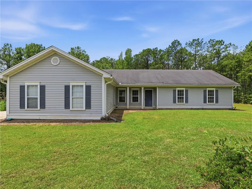 A classic ranch home nestled among a lush tree line, offering serene privacy and a spacious lawn.