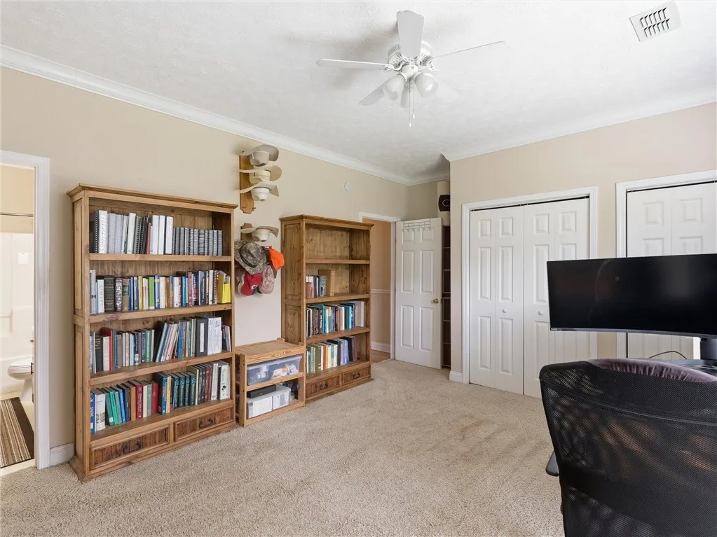 A versatile space features built-in bookcases and soft carpeting, perfect for a home office or a secondary bedroom.