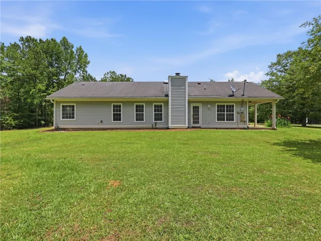 A sprawling lawn surrounds this charming residence, featuring a covered porch and ample outdoor space.