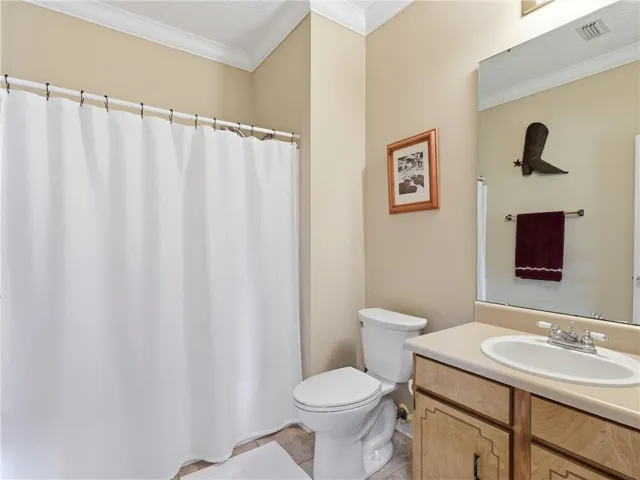 A well-maintained bathroom with a spacious vanity, full shower, and crown molding.