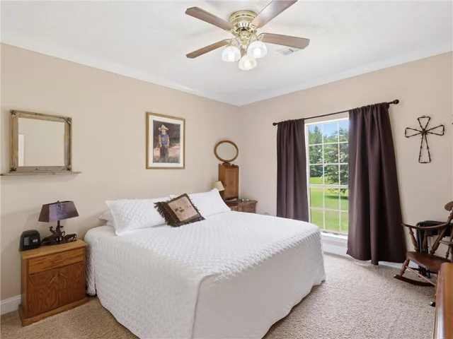 Comfortable bedroom offers a serene retreat with a bright window framing outdoor greenery.