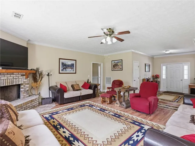 A welcoming living area boasts warm wood-tone flooring, a cozy fireplace, and crown molding.