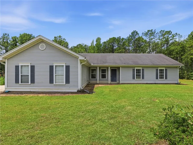 A classic ranch home nestled among a lush tree line, offering serene privacy and a spacious lawn.