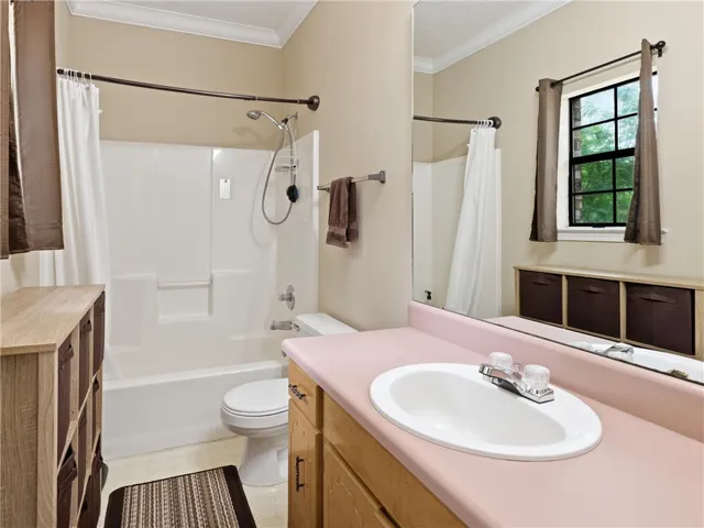 Functional bathroom featuring a tub-shower combination, single vanity with a large mirror, and ample natural light.