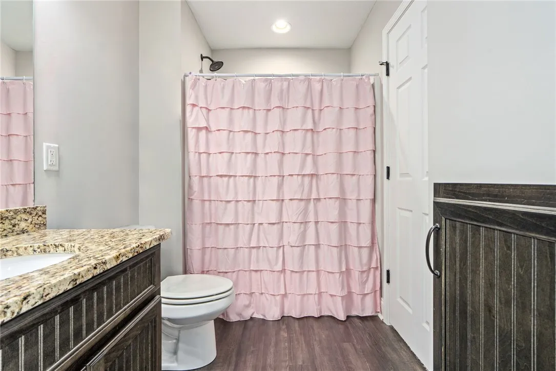 Granite counters and wood plank flooring define this well-appointed bathroom space.