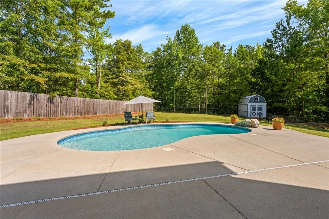 An inviting backyard oasis awaits with a sparkling pool and ample space for outdoor enjoyment.