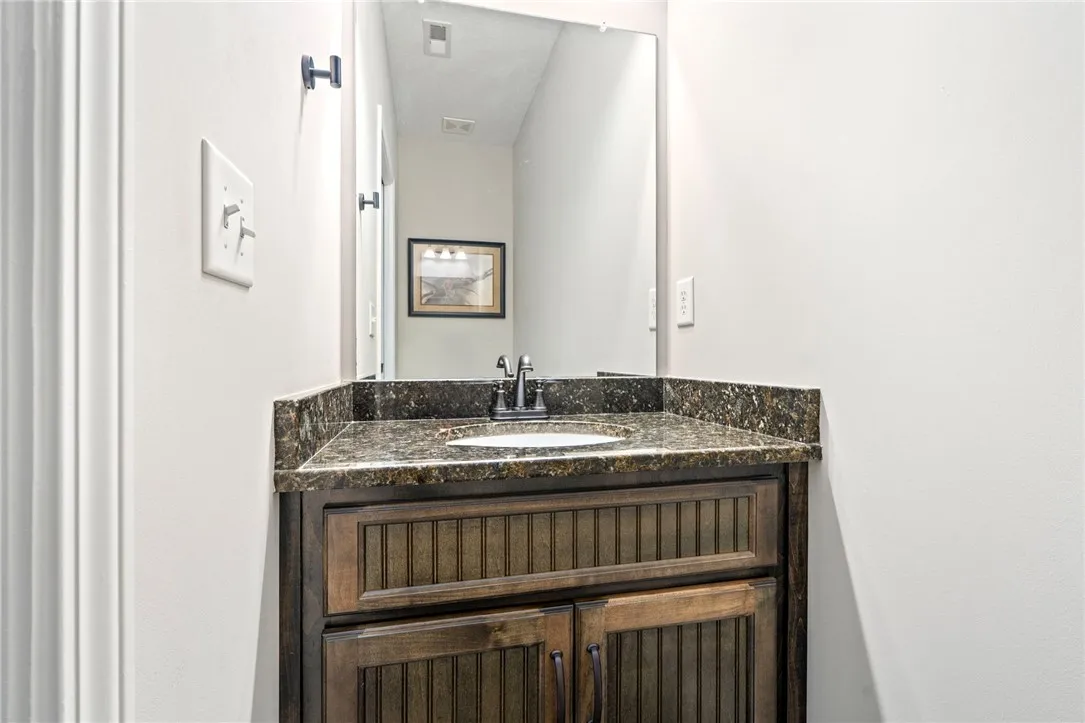 A dark wood vanity with a stone countertop and a simple mirror creates a functional powder room.