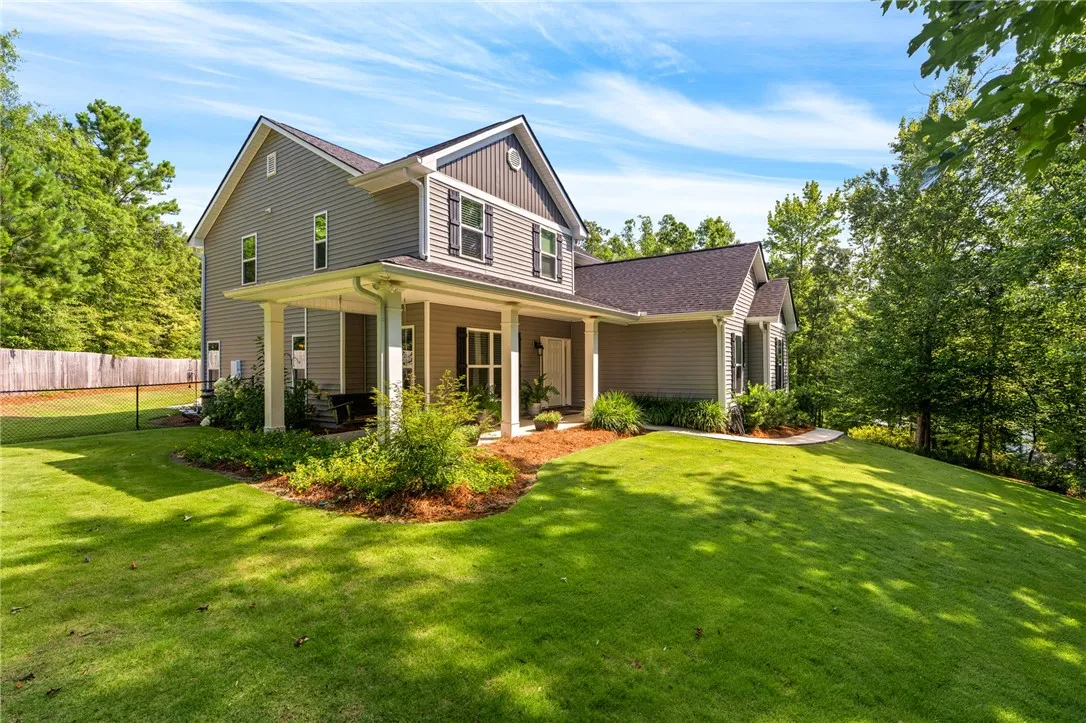 A welcoming front porch leads to this modern home nestled in a lush, green landscape.