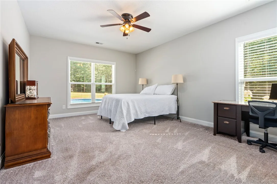 Well-lit sleeping quarters with a ceiling fan, plush carpet, and ample natural light.