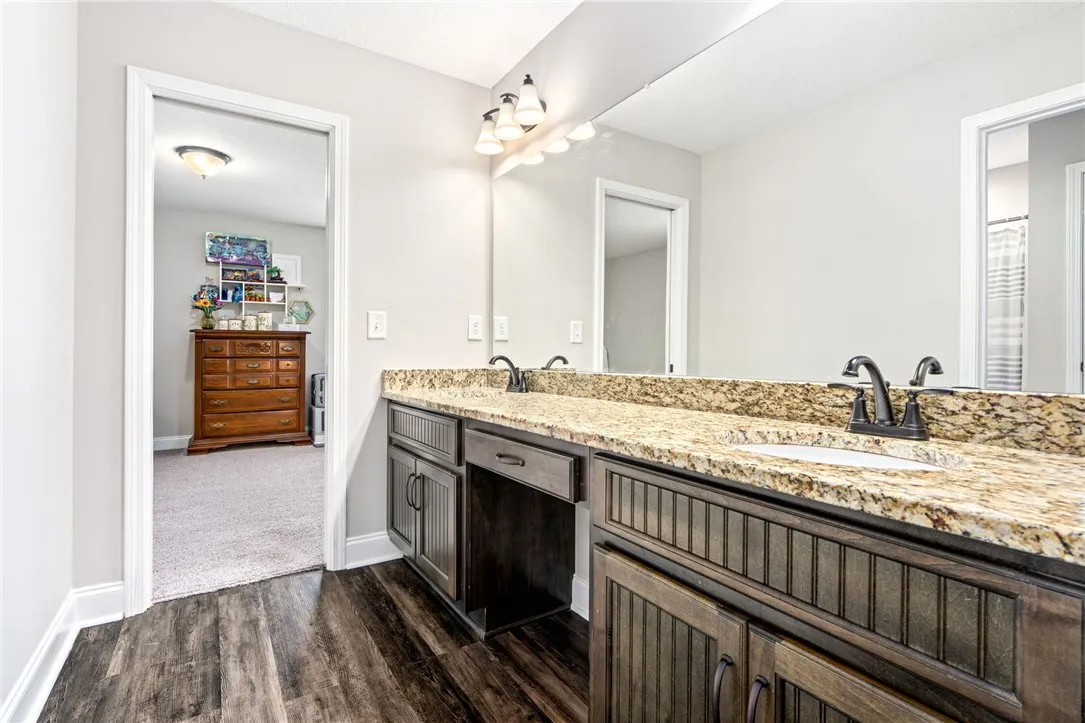 Double vanity with granite counters and rich cabinetry elevate this well-appointed primary bathroom.