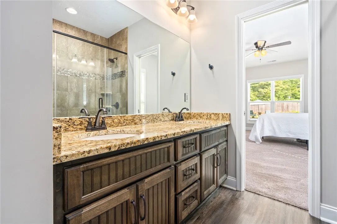Double vanity with granite counters and a glass-enclosed shower complement this well-appointed bathroom.