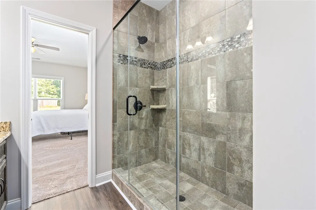 A spacious, naturally illuminated shower with modern tile and an adjacent bedroom for seamless transitions.
