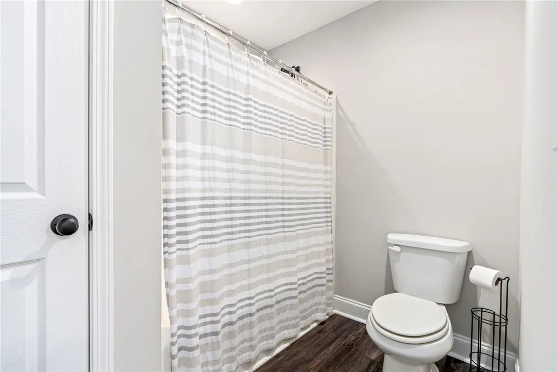 Functional full bathroom with shower and rich dark-tone flooring.