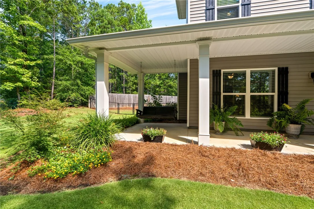 A welcoming covered porch with a swing invites relaxation amidst verdant landscaping.