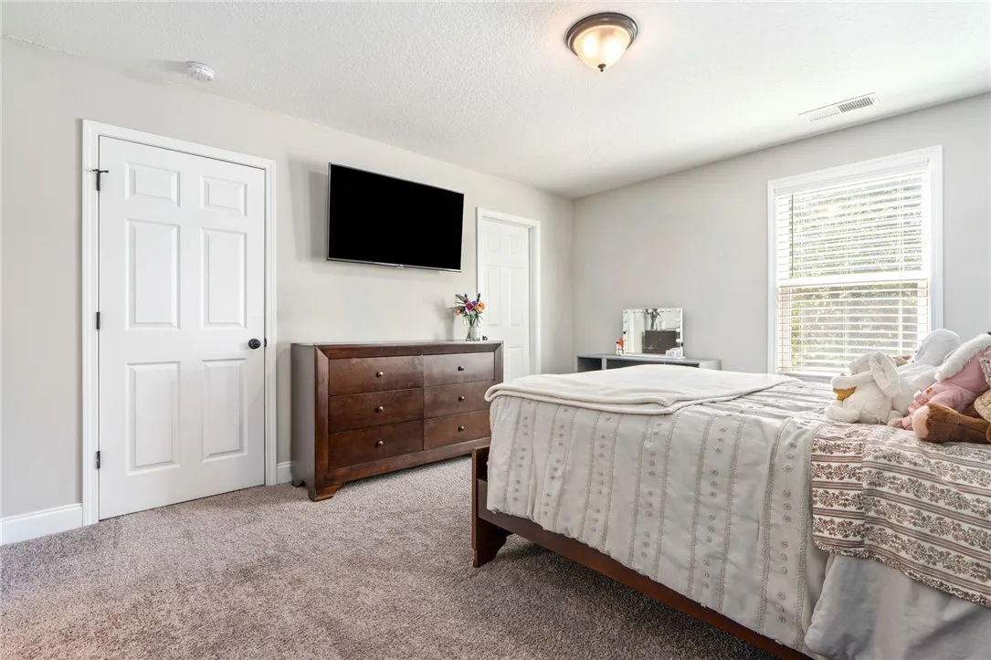 A comforting bedroom space featuring soft carpeting and a window with natural light.