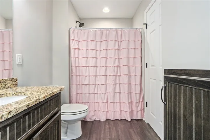 Granite counters and wood plank flooring define this well-appointed bathroom space.