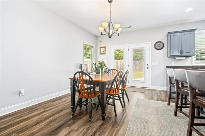 Dining area with rich hardwood flooring opens to the backyard.