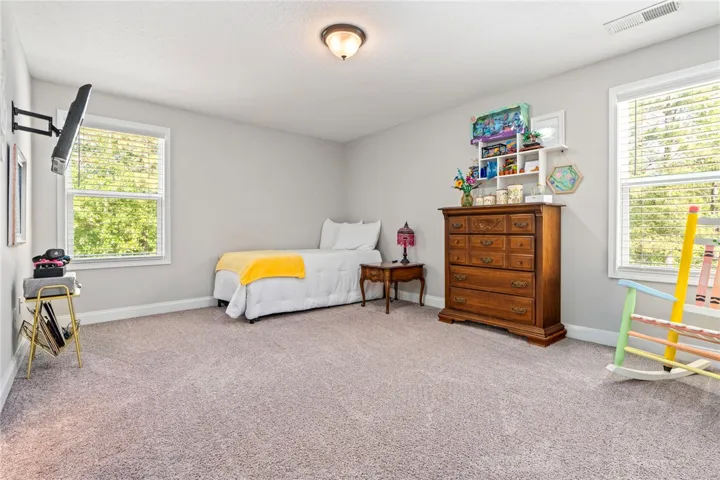 A quiet bedroom offering soft carpeting and generous natural light from multiple windows.