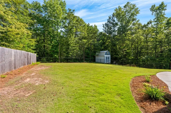 A verdant lawn provides ample space for recreation, complemented by a charming shed and mature trees.