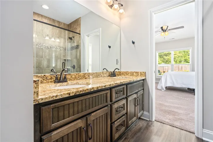 Double vanity with granite counters and a glass-enclosed shower complement this well-appointed bathroom.