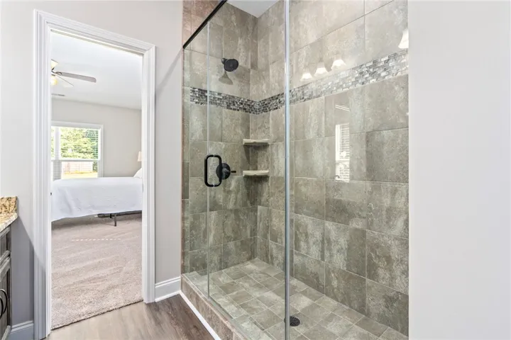 A spacious, naturally illuminated shower with modern tile and an adjacent bedroom for seamless transitions.