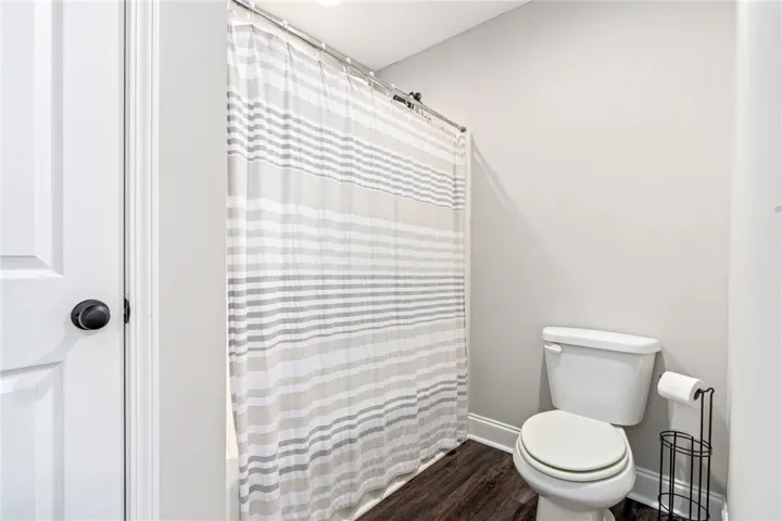 Functional full bathroom with shower and rich dark-tone flooring.