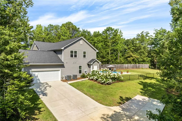 A private backyard oasis features a fenced-in pool surrounded by lush landscaping and mature trees.