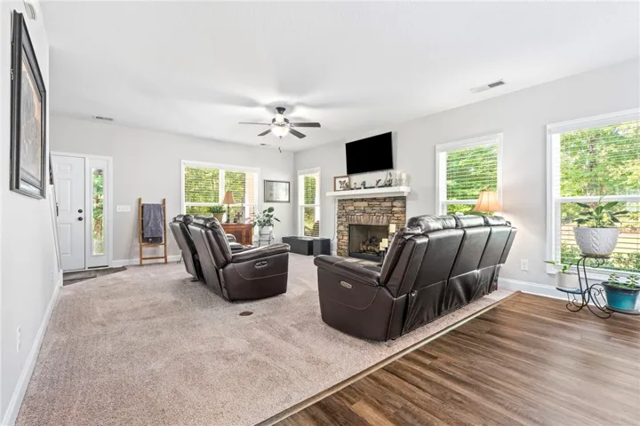 A spacious living area with a stone fireplace and varied flooring offers a warm welcome.