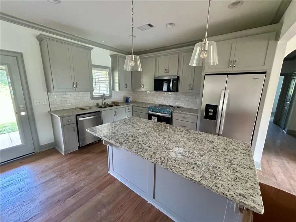 A well-appointed culinary space featuring sleek cabinetry, granite island, and modern stainless steel appliances.