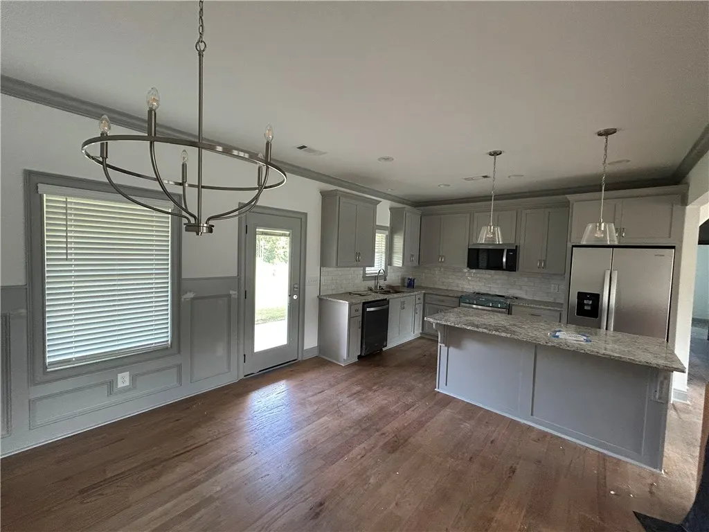 A well-appointed kitchen features stainless steel appliances, granite countertops, and rich hardwood flooring, ready for culinary endeavors.