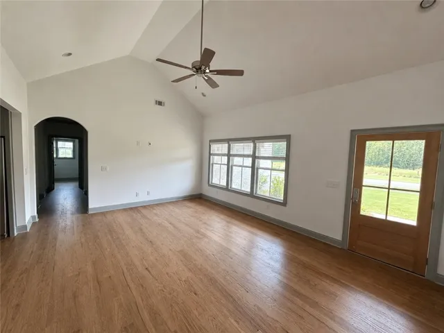 A spacious living area with soaring vaulted ceilings and natural wood flooring.