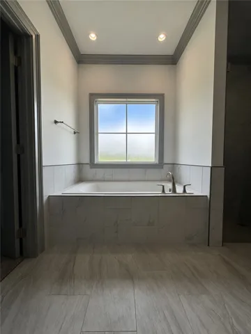 Indulge in a tranquil bathing experience within this well-appointed bathroom featuring a deep soaking tub and sleek tilework.