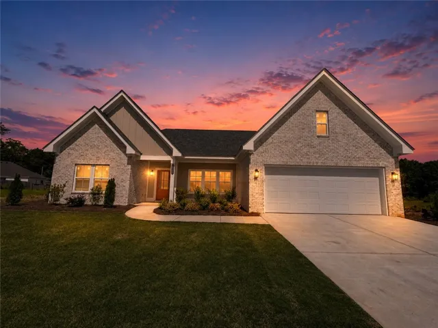 Twilight paints a picturesque backdrop for this inviting home, showcasing a manicured lawn and attached garage.