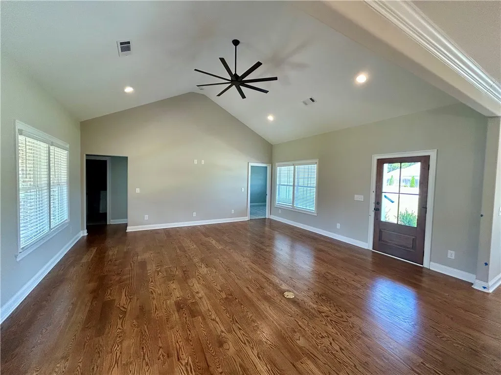 Rich hardwood floors complement the vaulted ceilings and recessed lighting in this spacious living area.