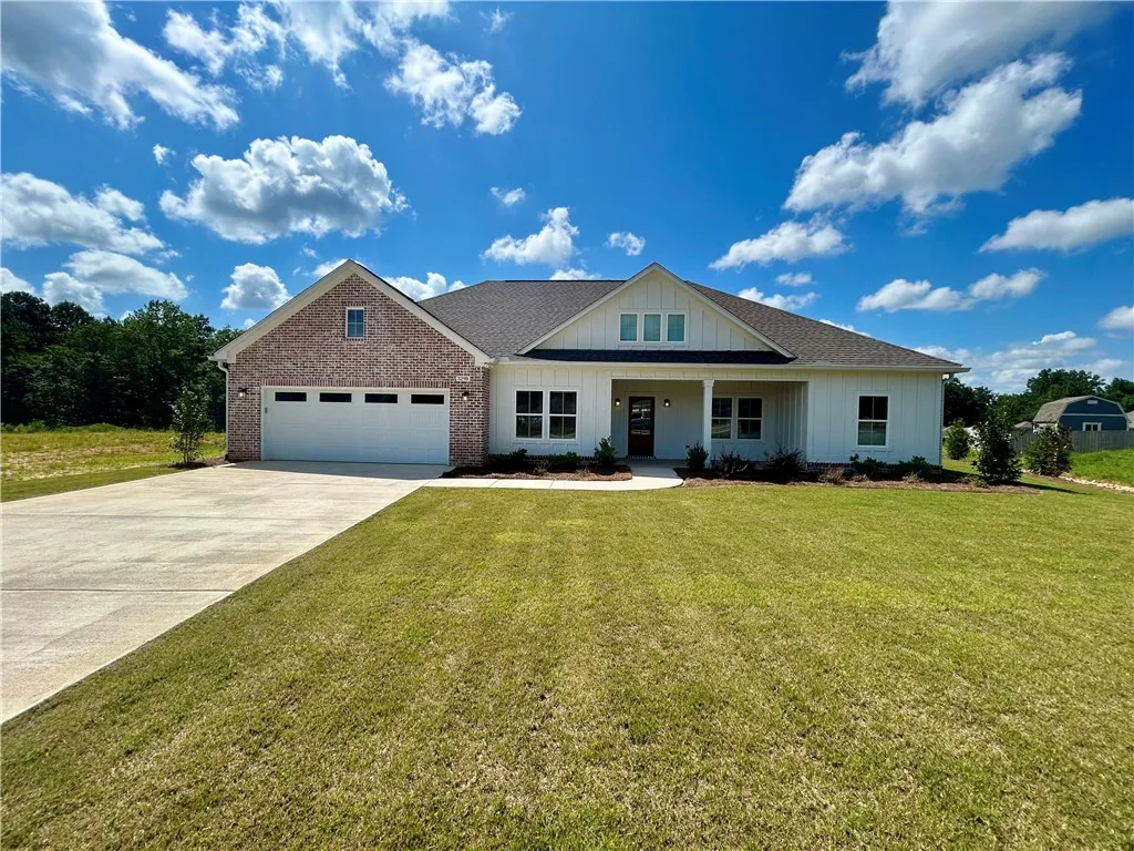 A well-maintained lawn welcomes you to this inviting residence, featuring a combination of brick and white siding under a clear blue sky.