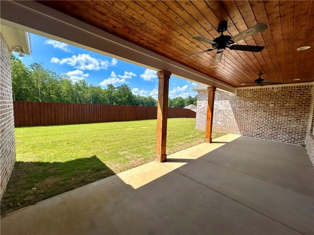 A spacious covered patio offers ample room for outdoor enjoyment and overlooks a verdant lawn.