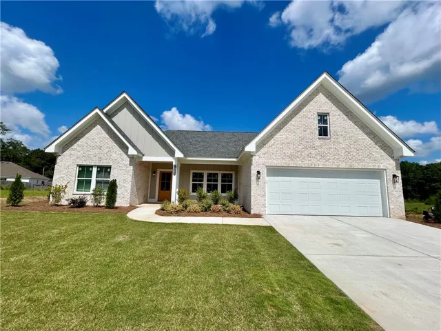 A newly constructed residence features a crisp white brick exterior, a practical two-car garage, and a welcoming curved pathway.