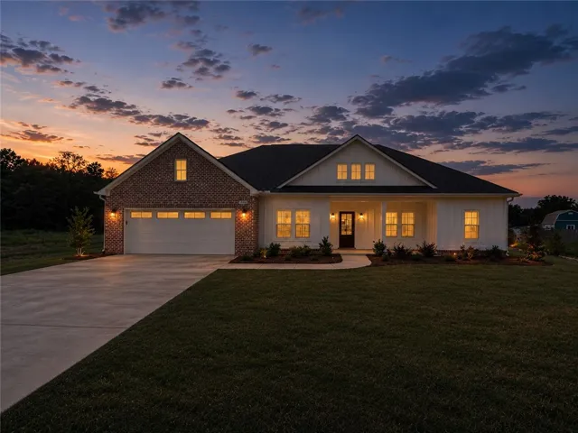 Gently illuminated at twilight, this residence features a welcoming covered entry and an attached garage, offering charm and convenience.