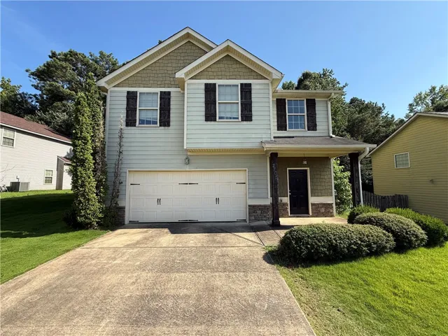 A welcoming facade features a covered entry, two-car garage, and neat landscaping.