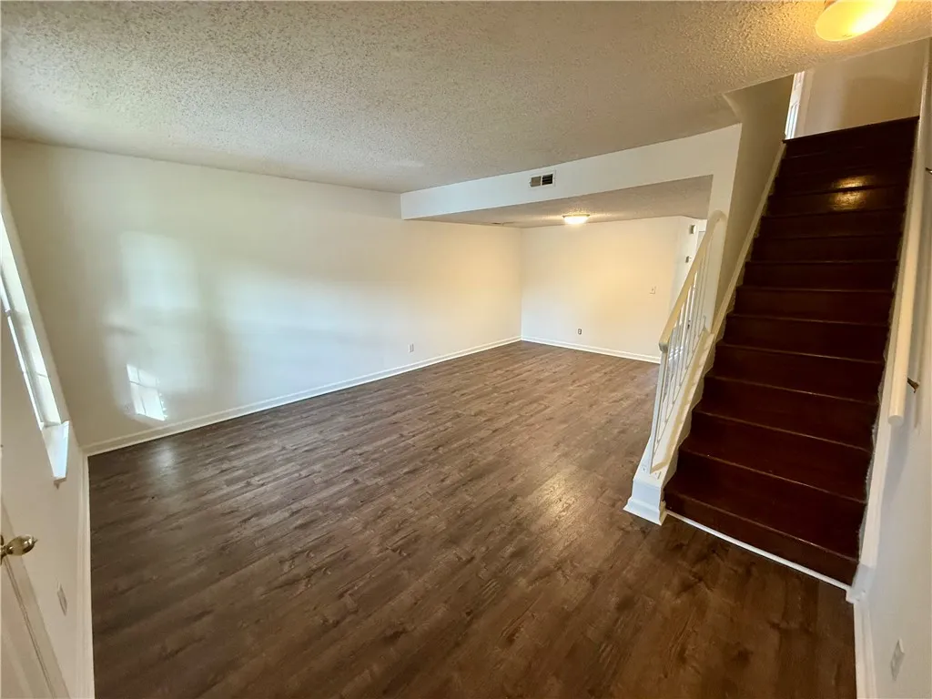 A versatile open-concept living area with rich wood-look flooring and easy access to the upper level.