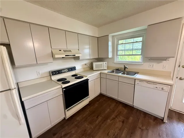 A functional kitchen provides ample cabinetry, a double basin sink, and essential appliances for everyday living.