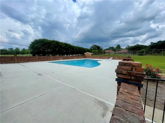 A refreshing swimming pool awaits, surrounded by a brick fence and ample patio space.