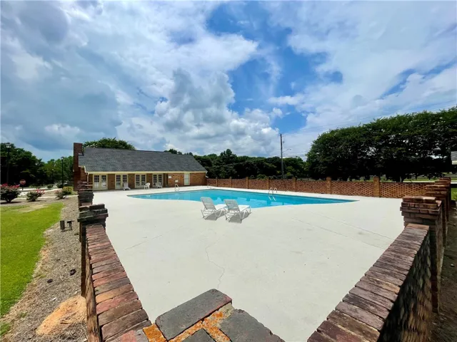An inviting community pool awaits, nestled beside a charming brick building with a classic gabled roof.