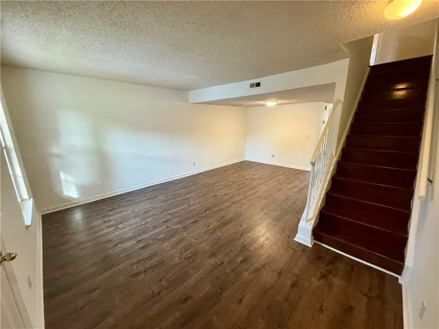 A versatile open-concept living area with rich wood-look flooring and easy access to the upper level.