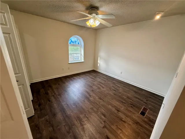 Rich wood flooring and a graceful arched window highlight this spacious room.
