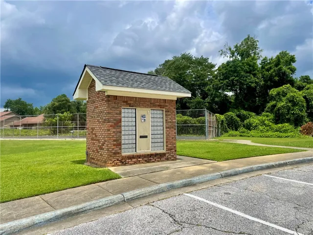 A quaint brick mail kiosk stands ready for community deliveries amidst well-tended green space and mature foliage.
