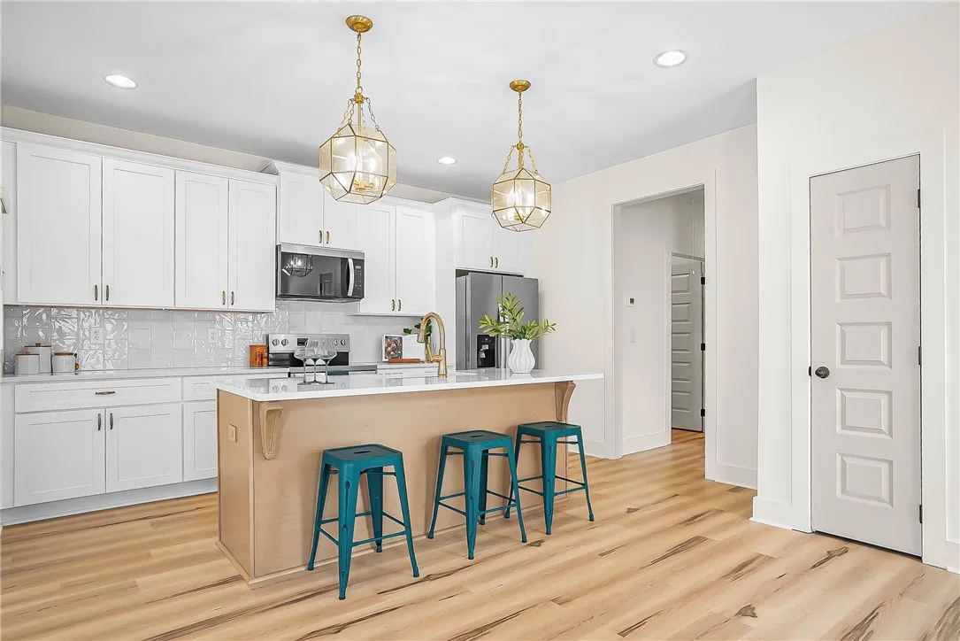 A well-lit kitchen with sleek white cabinetry and a central island creates an inviting space for hosting.