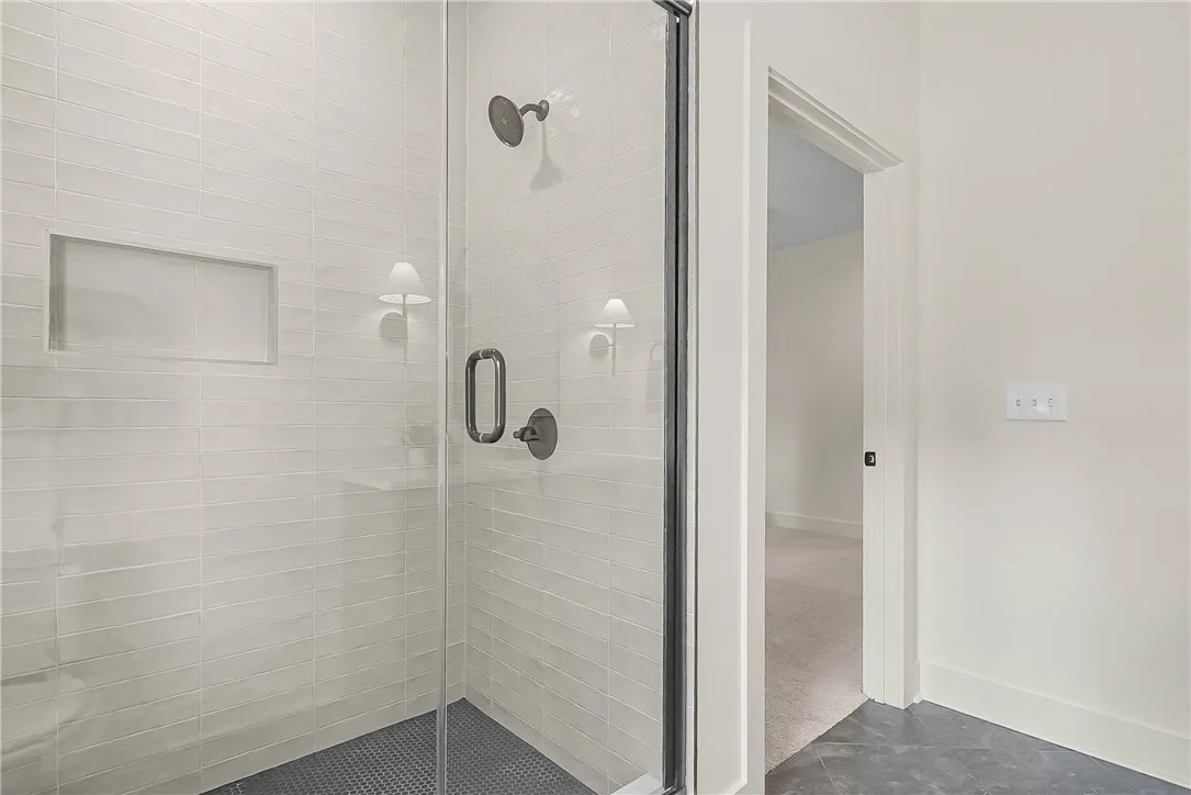 Primary bathroom features a sleek walk-in shower fully tiled walls & floor with semi-framed modern glass door.